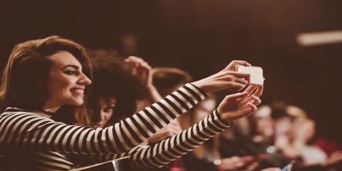 Young people at the concert, taking selfie using mobile